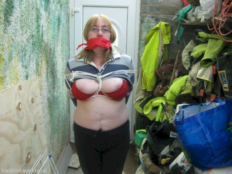 Mature woman is silenced with a gag while her tits are tied up with rope