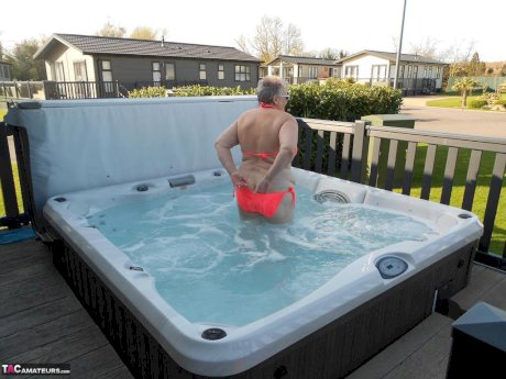 Fat nan bares her boobs while in a patio hot tub before getting naked on a bed