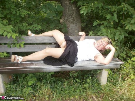 Mature amateur whore Caro masturbating on the bench in the woods