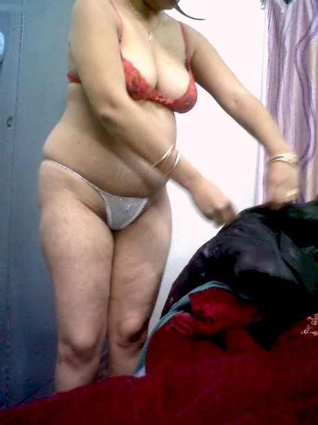 Fat Indian woman hides her face while adorned in a bra and thong